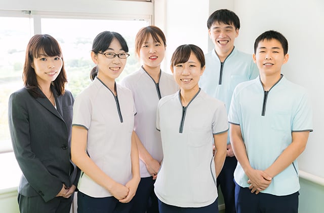介護施設のスタッフチームが明るく笑顔で並んで立つ集合写真